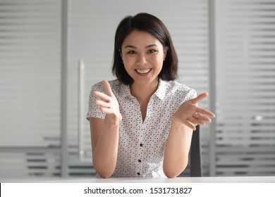Smiling young Asian businesswoman looking at camera and talking, making video call, mentor coach tutor recording webinar, online course, teaching language, hr manager holding distance job interview