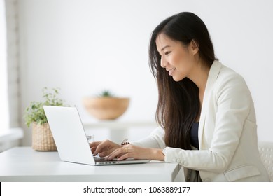 Smiling Young Asian Businesswoman Using Computer At Home Office Workplace, Happy Korean Employee Working On Laptop, Attractive Japanese Or Chinese Woman Student Studying Communicating Online With Pc