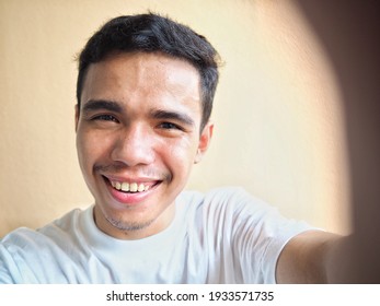 A Smiling Young Asian Man Taking A Selfie.