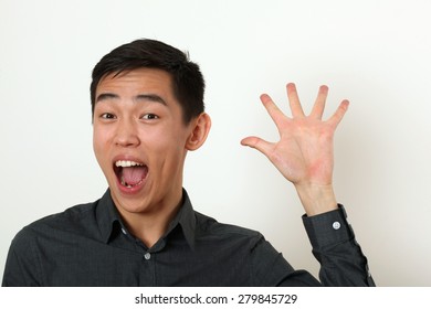 Smiling Young Asian Man Waving His Palm And Looking At Camera.