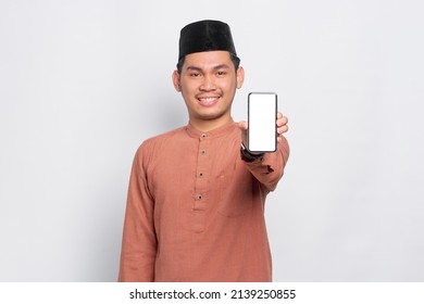 Smiling Young Asian Muslim Man Showing Mobile Phone Blank Screen Recommending App Isolated Over White Background