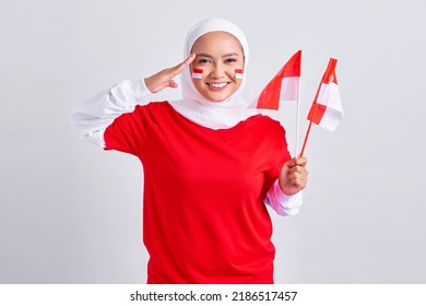 Smiling young Asian muslim woman in red white t-shirt holding flag indonesian to celebrating indonesian independence day on 17 august and showing respect gesture isolated on white background