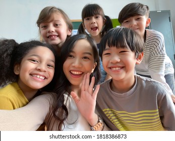 Smiling young Asian teacher making selfie with her schoolchildren in classroom. Elementary school,technology, children and people concept - Powered by Shutterstock