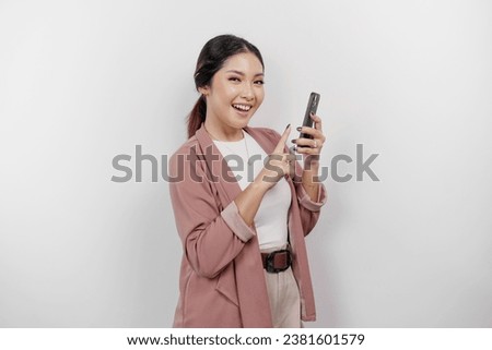 Smiling young Asian woman employee wearing cardigan while holding her phone, isolated by white background