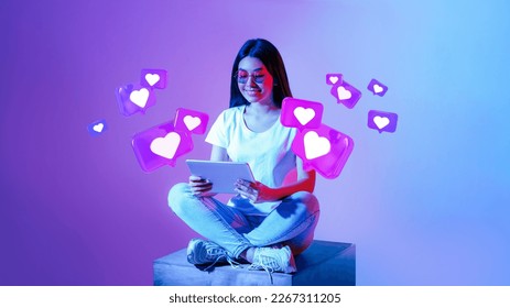 Smiling young asian woman in glasses typing on tablet, has romantic chat with hearts on neon background, studio, panorama. Dating app remotely, love and relationships at Valentine day, new normal - Powered by Shutterstock