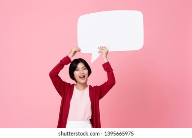 Smiling Young Asian Woman Holding Empty Speech Bubble In Pink Studio Background