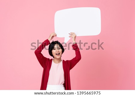 Smiling young Asian woman holding empty speech bubble in pink studio background