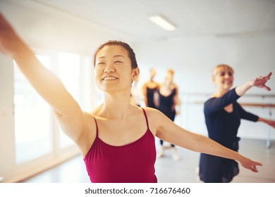 Smiling Young Asian Woman Leading A Group Of Senior Women During A Ballet Class In A Dance Studio