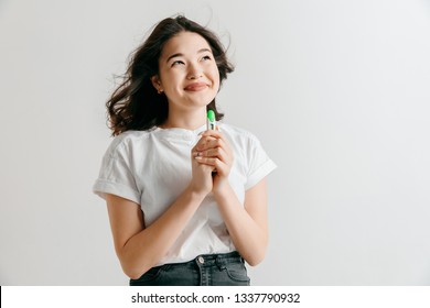 Smiling Young Asian Woman Looking On Pregnancy Test At Studio