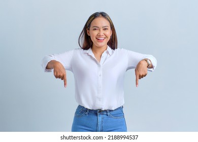 Smiling Young Asian Woman Pointing Fingers Down, Inviting People To Follow Isolated Over White Background