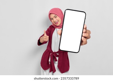 Smiling young Asian woman showing smartphone with blank screen and thumbs up isolated on white background - Powered by Shutterstock