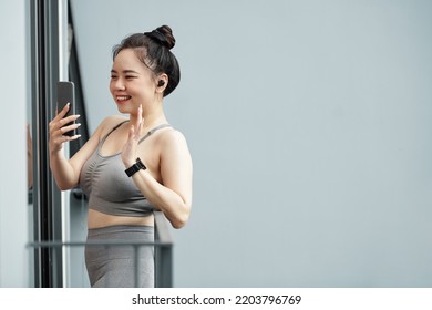 Smiling Young Asian Woman Standing On Apartment Balcony And Video Calling Her Friend