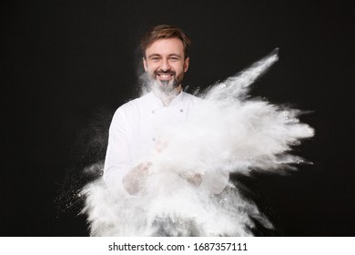 Smiling Young Bearded Male Chef Cook Or Baker Man In White Uniform Shirt Posing Isolated On Black Background Studio Portrait. Cooking Food Concept. Mock Up Copy Space. Clapping Hands, Throwing Flour