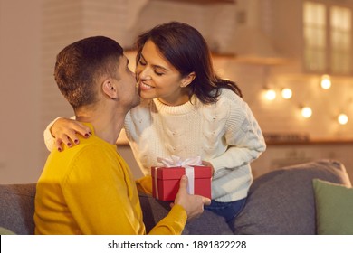 Smiling young beautiful happy couple giving presents and kissing at home during Valentines day celebrating together. Love, Valentines day, togetherness, birthday, anniversary, dating concept - Shutterstock ID 1891822228