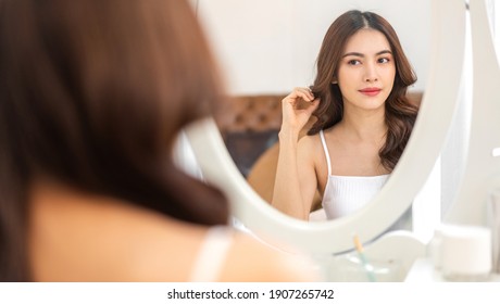 Smiling Of Young Beautiful Pretty Asian Woman Clean Fresh Healthy White Skin Looking At Mirror.asian Girl Touching On Her Face With Hand And Applying Cream At Home.spa And Beauty Concept