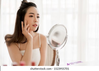 Smiling young beautiful woman fresh healthy skin looking on mirror with makeup cosmetics set at home.facial beauty and cosmetic concept - Powered by Shutterstock