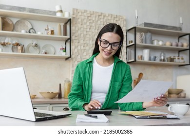 Smiling young beautiful woman reading banking paper notification about last mortgage payment while calculating budget at home. Happy millennial girl feeling excited of good news in letter notice. - Shutterstock ID 2185002385