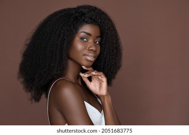 Smiling young black African woman model with curly afro hair, healthy flawless radiant smooth face skin care isolated on brown background. Ethnic beauty, luxury skincare, makeup concept. Portrait