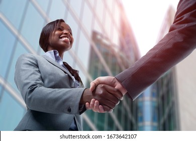 Lächeln junge schwarze Geschäftsfrau, die mit einem weißen Geschäftsmann die Hände schüttelt