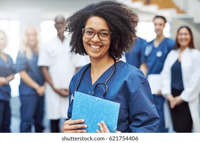 Smiling young black female doctor standing in front of medical team at hospital
