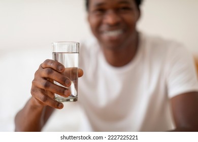 Smiling Young Black Guy Giving Glass With Mineral Water At Camera, Happy Handsome African American Man Enjoying Refreshing Drink, Recommending Healthy Liquid, Closeup Shot With Selective Focus - Powered by Shutterstock