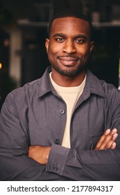 Smiling Young Black Male Standing In Office Looking At Camera With Arms Crossed