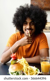 Smiling Young Black Man Eating Fries At Restaurant 