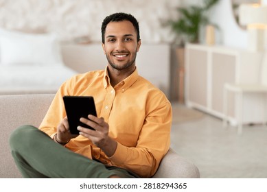 Smiling Young Black Man Using Tablet In Modern Living Room, Business Concept