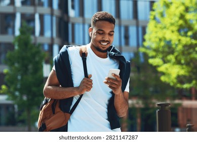 Smiling Young Black Man Using Smartphone Outdoors In Urban Setting, Lifestyle Concept