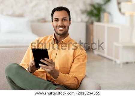 Smiling Young Black Man Using Tablet In Modern Living Room, Business Concept