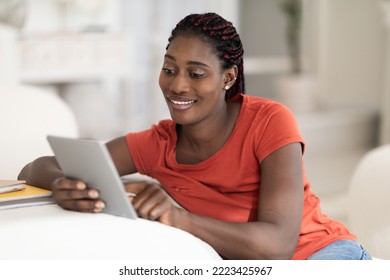 Smiling young black woman relaxing on digital tablet at home, happy millennial african american female using modern gadget while resting in living room, enjoying weekend pastime, closeup shot - Shutterstock ID 2223425967