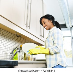 Smiling Young Black Woman Washing Dishes In Kitchen