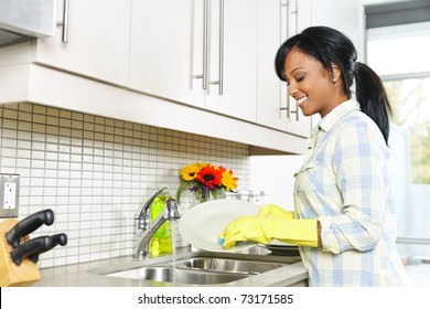 Smiling Young Black Woman Washing Dishes In Kitchen