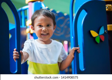 Smiling Young Boy Holding On From A Kids Playground Jungle Gym With An Excited Look And Ready To Have Fun.