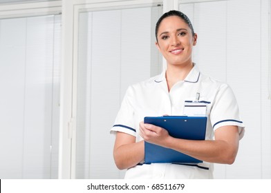 Smiling Young Brunette Female Nurse Looking At Camera At Hospital