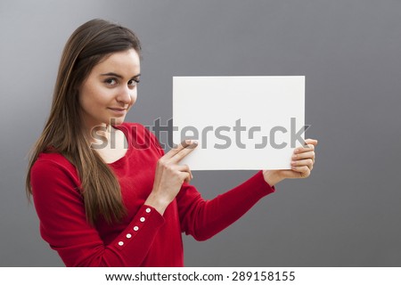 smiling young brunette wearing red holding a blank communication board with teasing news on