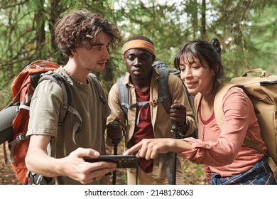 Smiling Young Brunette Woman Pointing At Online Map On Phone While Explaining Geolocation To Friends At Hike