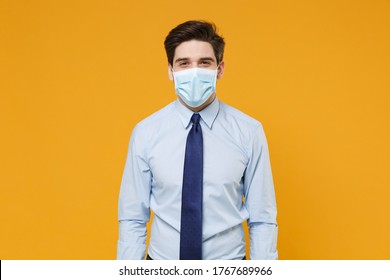 Smiling Young Business Man In Classic Blue Shirt Tie Sterile Face Mask Isolated On Yellow Background Studio. Epidemic Pandemic Rapidly Spreading Coronavirus 2019-ncov Sars Covid-19 Flu Virus Concept