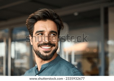 Smiling young business man standing looking away in office. Happy Latin businessman, male entrepreneur, professional manager or company employee worker close up portrait. Copy space