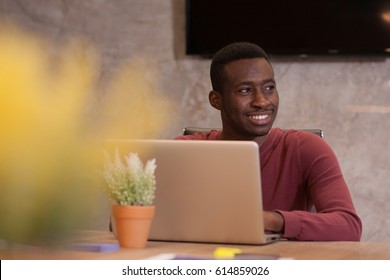 Smiling young business owner is working at his desk on his laptop
