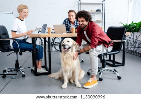 smiling young business people looking at dog while working in office