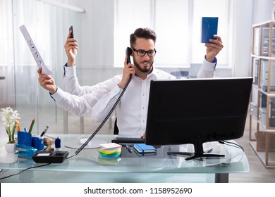 Smiling Young Businessman Doing Multitasking Work At Workplace - Shutterstock ID 1158952690