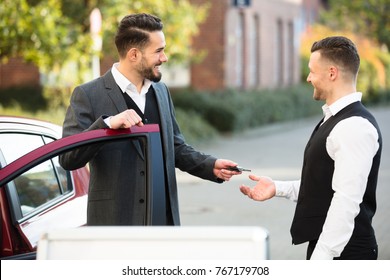 Smiling Young Businessman Standing Beside Car Giving Key To Valet