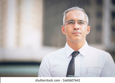 Smiling young businessman working online with a digital tablet while standing outside of modern office building  looking the city at sunshine. - Powered by Shutterstock