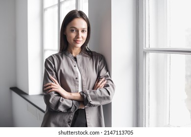 Smiling Young Businesswoman Portrait. Self Confident Young Woman With Crossed Arms In Office. People, Candid Portraits, Business, Lifestyle Concept