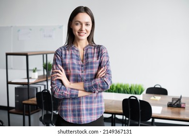 Smiling Young Businesswoman Portrait. Self Confident Young Woman With Crossed Hands In Office. People, Candid Portraits, Business, Lifestyle Concept