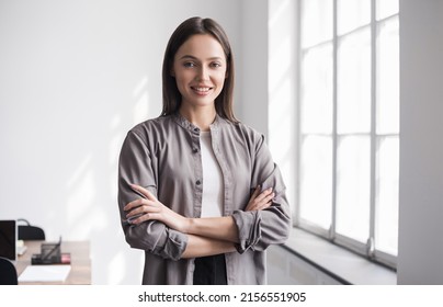 Smiling Young Businesswoman Portrait. Self Confident Young Woman With Crossed Arms In Office. People, Candid Portraits, Business Casual, Self Confidence, Leadership Concepts