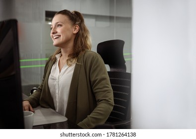 Smiling young businesswoman sitting at her desk in a modern office and working on a computer - Shutterstock ID 1781264138