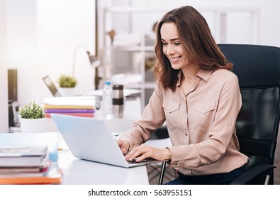 Smiling Young Businesswoman Typing In The Office