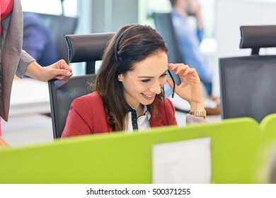 Smiling young businesswoman using headset in office - Powered by Shutterstock